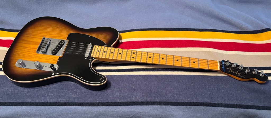 Fender American Ultra Luxe Telecaster in 2-color burst pictured atop a colorful blanket
